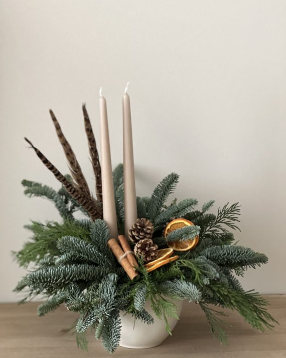 Centro navideño natural con velas color arena, piñas y rodajas de naranja