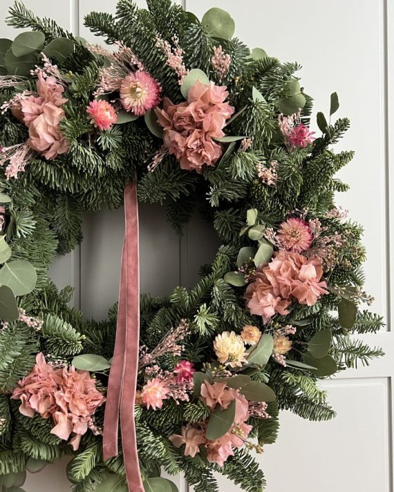 Primer plano de hortensia preservada, flor de papel y brooms rosa en corona navideña
