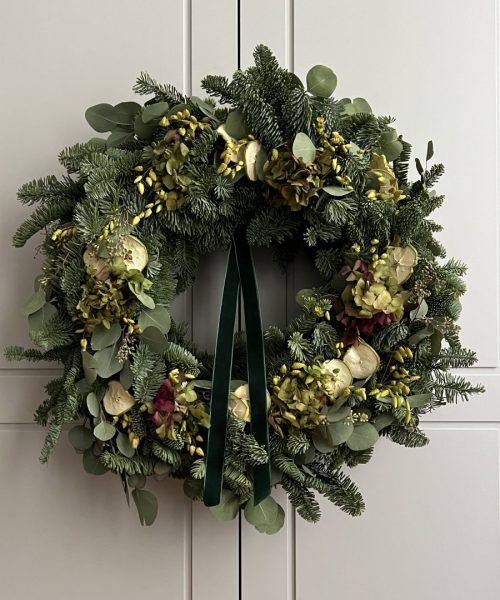 Lazo de terciopelo verde en corona artesanal navideña Detalle de lazo de terciopelo sobre corona de Adviento con abeto y hortensia