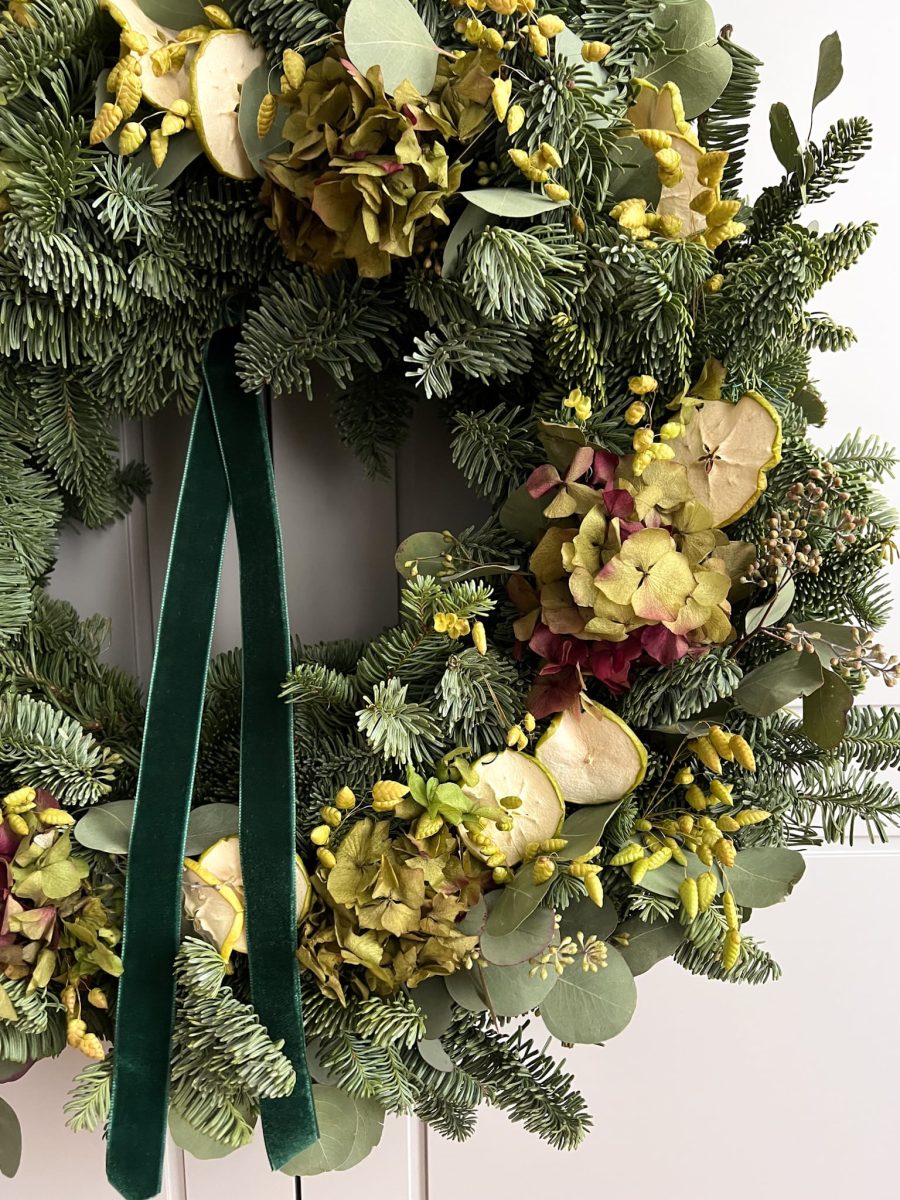 Primer plano de corona con hortensia preservada, briza seca y fruta natural
