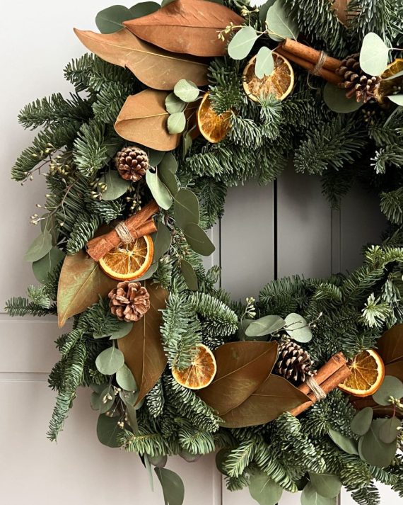 Detalle de corona navideña con canela, naranja seca y abeto natural