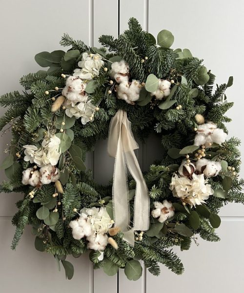 Corona navideña natural con flor de algodón y hortensia blanca en composición serena