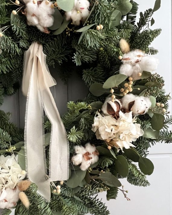 Primer plano de flor de algodón seca y lagurus beige en corona navideña nórdica